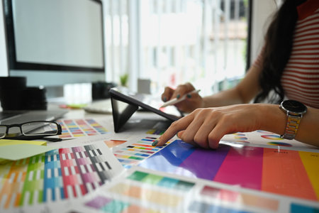 Closeup view female designer working with color palette, choosing color samples for design project at modern office.の写真素材