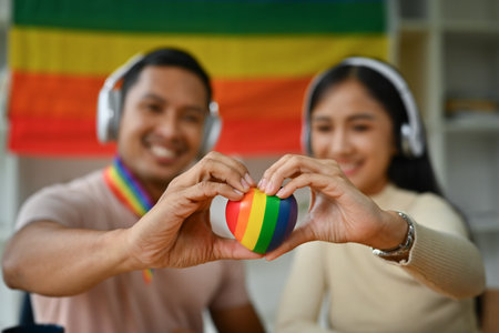 Male and female hands holding rainbow heart with smiling face. LGBTQ, human rights and equality social.の写真素材