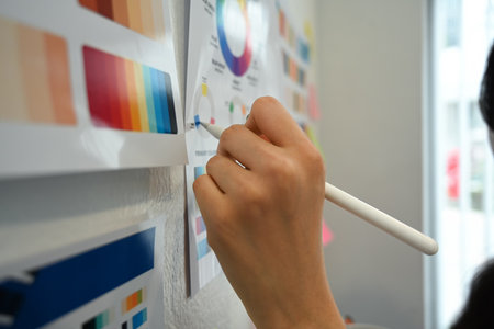 Closeup view of woman hand working with color palette, choosing color samples on whiteboard at graphic studio.の写真素材