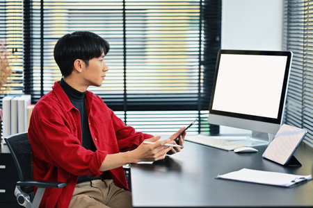 Portrait of young handsome Asian entrepreneur working on startup project at his modern office.の写真素材