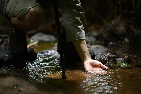 Man tourist hand touching clear water of mountain stream. Travel, adventure and active life concept.の写真素材