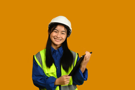 Asian girl holding helmet isolated on yellow background, future dream job career as engineer and architect.の写真素材