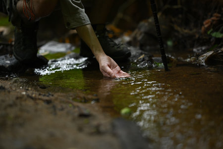 Male traveller hand touching clear water of mountain stream. Travel, adventure and active life...