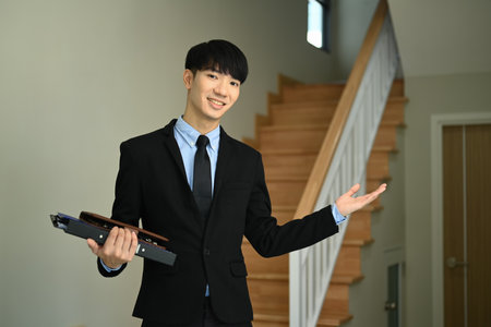 Confident male realtor standing in new house for sale ready to presenting offer. Real estate and property investment concept.の写真素材