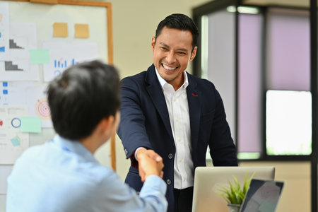 Confident businessman shaking hands with partner after closing deal or successful negotiations at meeting.の写真素材