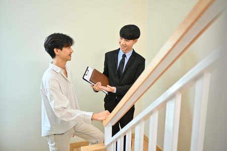 Smiling asian male real estate agent offering life insurance to client. Real estate mortgage and property investment.の写真素材