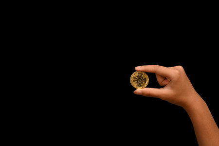 Man holding holding golden bitcoin on black background. Digital cryptocurrency and markets concept.
