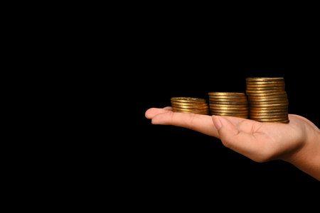 Unrecognizable woman hands holding gold coins on a dark background. Finance, investment and save money concept.の写真素材