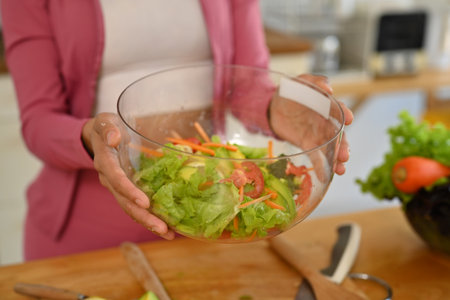 Young woman holding glass bowl of vegetable salad. Dieting, weight loss and healthy lifestyle concept.の写真素材