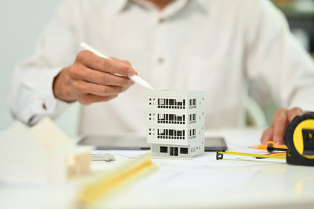 Closeup shot of architect man working with architectural model residential at office desk....