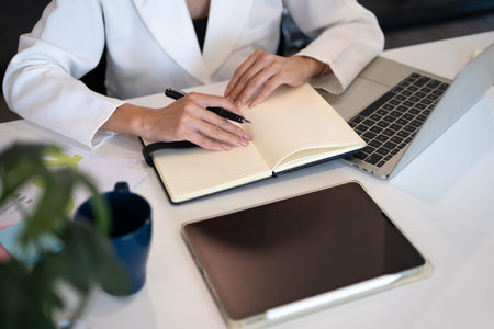 Female entrepreneur using laptop computer and writing planning daily appointment on notebook.の写真素材