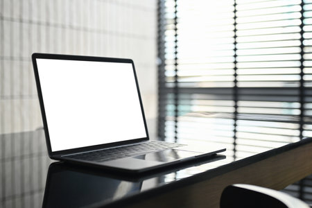 Laptop computer on black glass table in modern workplace. Empty display for your advertising text message.の写真素材