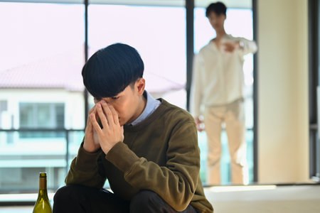 Upset alcoholic man quarreling with his boyfriend. LGBTQ relationship, alcohol addiction concept.の写真素材