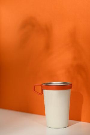 A stainless steel travel mug over orange background. Tumbler beverage container and Eco friendly...