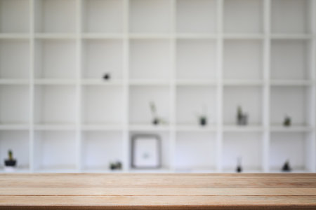 Empty wooden tabletop over a blurred white large bookshelves. Space for product display montage or design.の写真素材