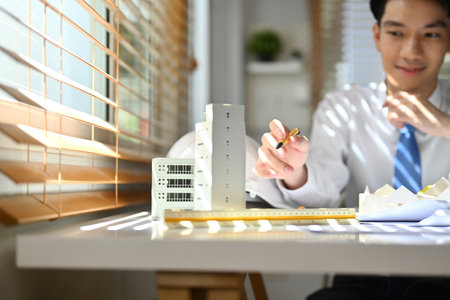 Cropped shot of architect man pointing at building model, working on project of residential at desk.の写真素材