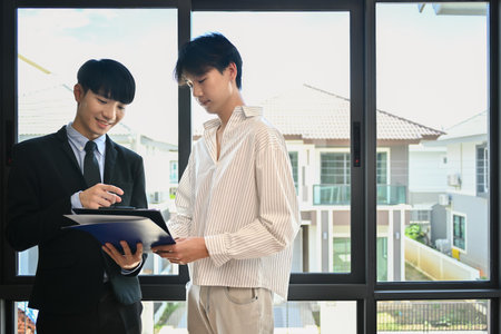 Happy male client making sale purchase, signing contract with real estate agent. First property purchase and home ownership.の写真素材