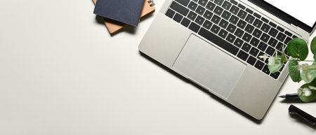 Laptop, notebooks pen and houseplant on white background. Flat lay, top view with copy space.の写真素材