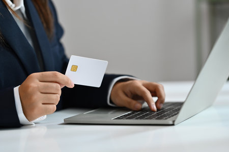 Close up businesswoman holding credit card and using laptop, making purchase, payments on webstore, paying bills.の写真素材