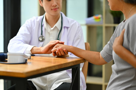 Doctor in white coat holding senior female patient hand, expressing sympathy and support. Medical healthcare concept.の写真素材