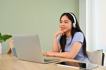 Young woman in headphone using laptop, working online, searching in internet. People and technology...
