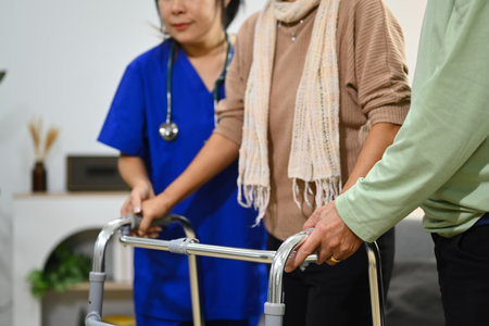 Practitioner nurse assisting senior female walking with walker. Healthcare service and rehabilitation.の写真素材