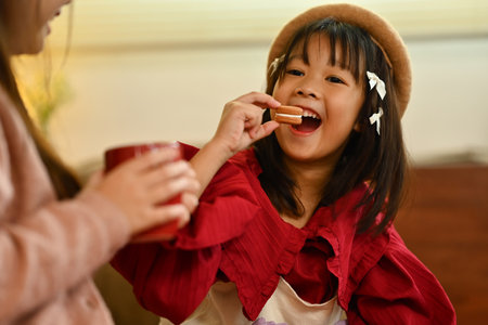 Cute girl enjoying holiday eating cookies and hot chocolate in living room, celebrating winter holidays at home.の写真素材