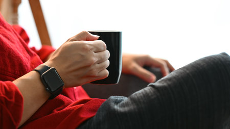Young man drinking hot coffee relaxing and spending free time in living room.の写真素材