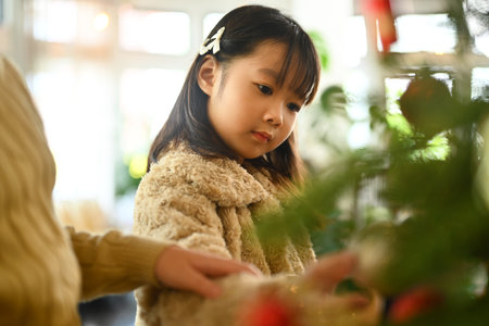 Image of adorable girl decorating Christmas tree preparing for Christmas holidays and happy new year.の写真素材