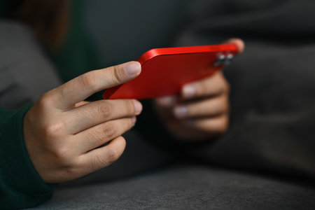 Close up young woman lying on sofa and watching social media videos on smartphone.の写真素材