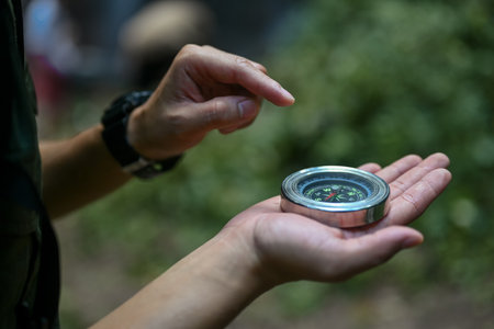 Close up view of male hiker using compass for directions while exploring nature in the forest.