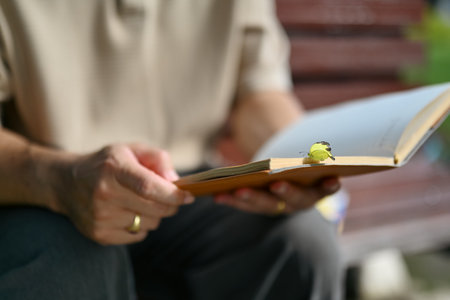 Peaceful middle age man sitting on bench at park and reading book.の写真素材