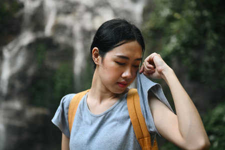 Tired female hiker taking a break and wiping sweat from her forehead.の写真素材