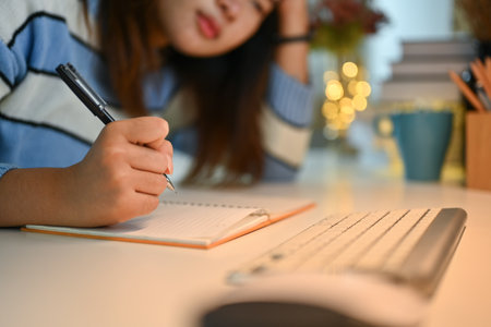 Bored asian woman sitting studying and doing homework a desk in living room.の写真素材