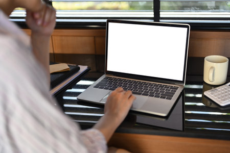 Cropped shot of young woman using laptop on black table near window.の写真素材