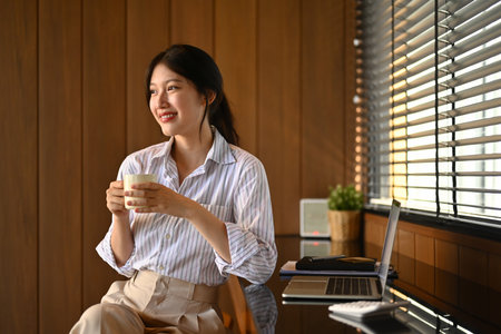 Portrait of successful businesswoman drinking coffee at modern workplace.の写真素材
