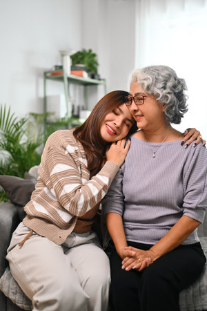 Smiling Asian woman embracing mature mother expressing unconditional love.の写真素材