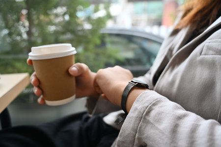 Businesswoman looking on her wrist watch while sitting near office window.