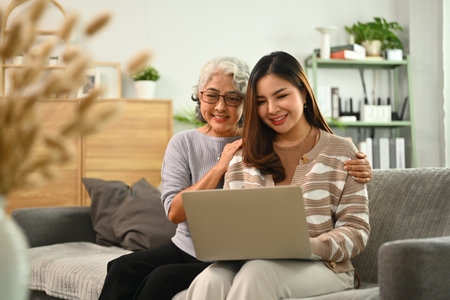 Pretty young woman and mature mother shopping online or browsing internet on laptop.の写真素材