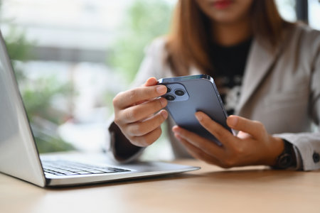 Modern businesswoman sitting front of laptop at coffee shop and using mobile phone.の写真素材