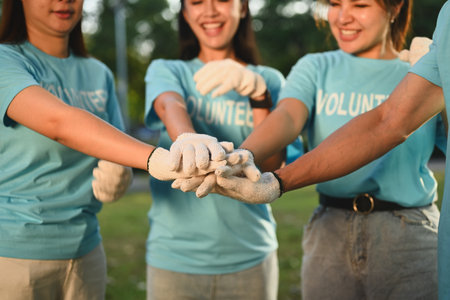Group of young volunteers stacking hands together showing teamwork spirit. Charity and ecology concept.の写真素材