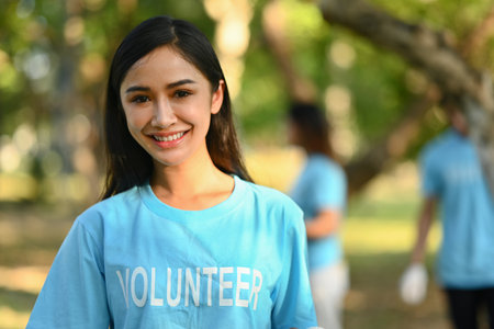 Portrait female volunteer in blue uniform smiling at camera while standing outdoor. Charity and community service concept.の写真素材