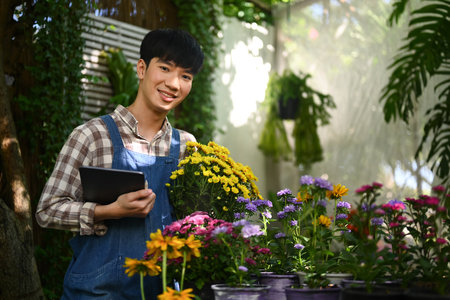 Handsome Asian male florist holding fresh flowers working in his floral shop.の写真素材