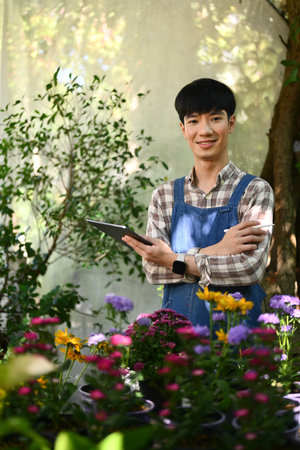 Portrait of Asian man small business entrepreneur in apron using digital tablet at his florist shop.の写真素材
