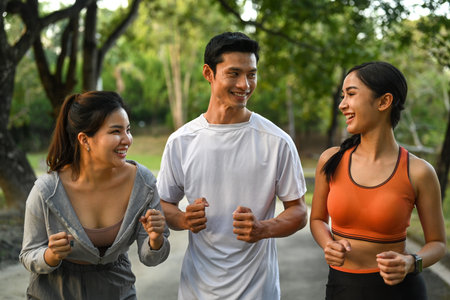 Cheerful male and female friends jogging in public park. Sport, friendship and healthy lifestyle conceptの写真素材