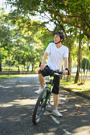 Happy retired man riding bicycle in the public park. Health care and wellbeing concept.の写真素材