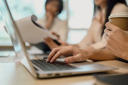 Close up female employee hand typing on laptop while sitting at meeting tableの写真素材