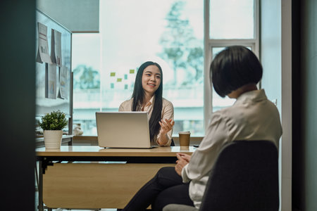 Beautiful young businesswoman talking or planning project with senior colleague at officeの写真素材