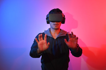 Smiling man wearing VR headset feeling excited and trying to touch something with handsの写真素材