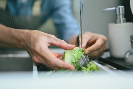 Closeup hands washing vegetables in the kitchen sink and preparing healthy foodの写真素材